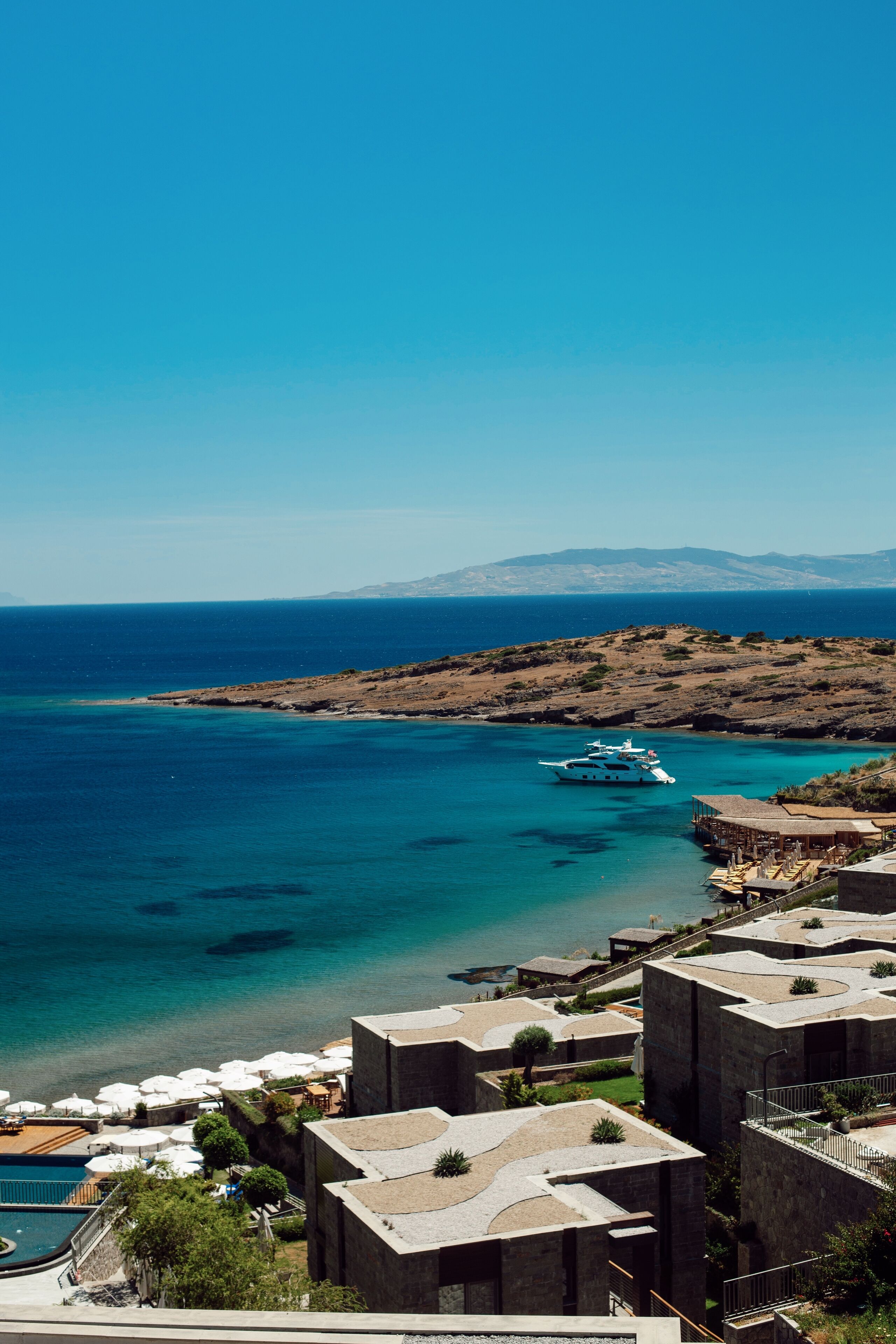 Un hôtel en bord de mer doté d’une piscine, d’un espace extérieur aménagé et offrant une vue sur la mer et les montagnes.