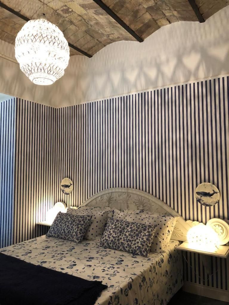 A bed with a floral pattern, striped wallpaper, and a round wall decoration.
