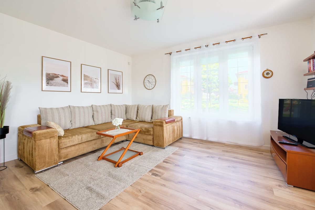 Una sala de estar con un sofá modular, una mesa de centro, un televisor y una estantería.