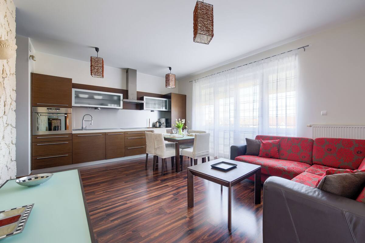 Una sala de estar moderna con un sofá, una mesa de comedor y una zona de cocina con armarios y un microondas.