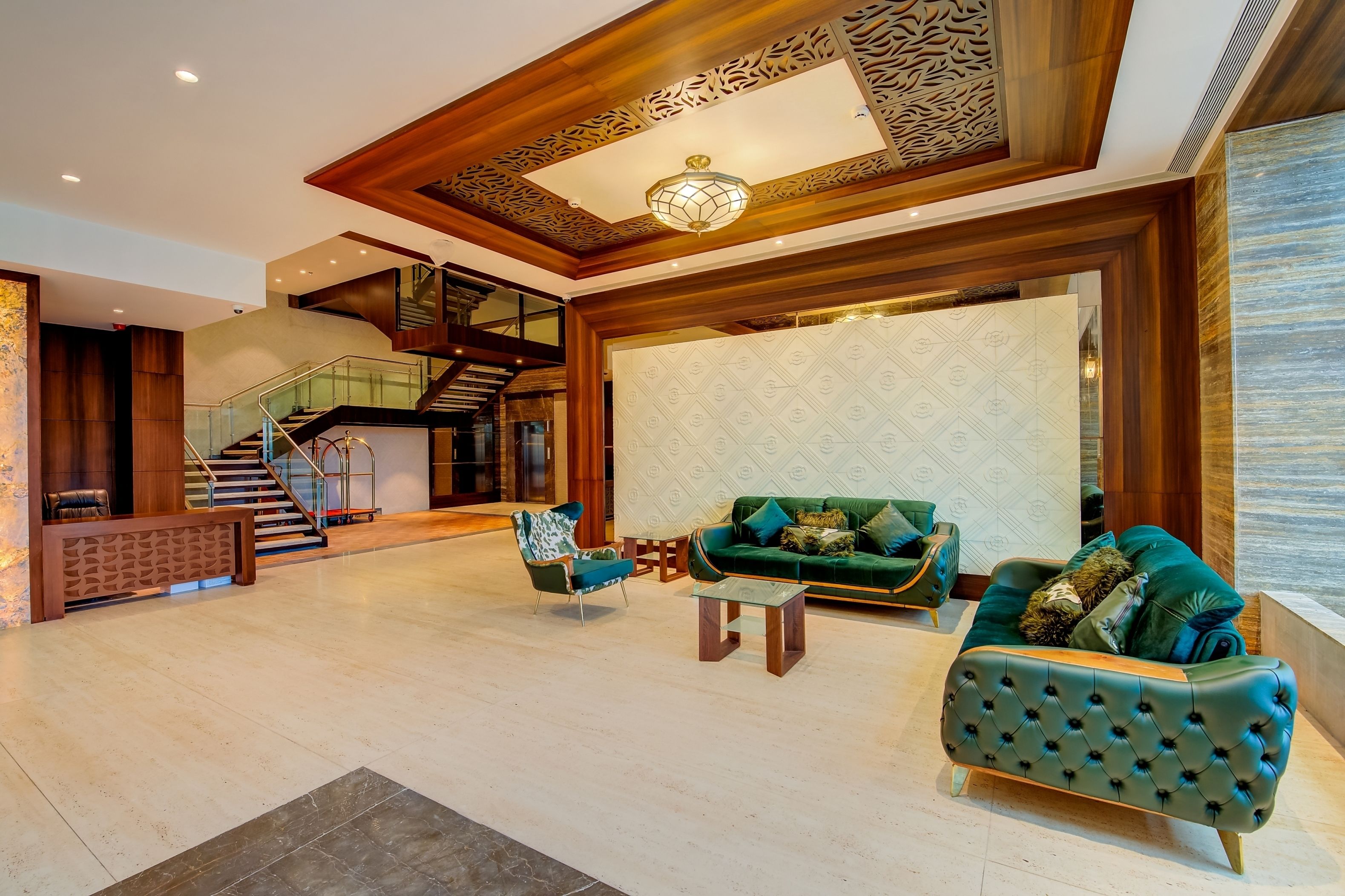 A spacious lobby with a staircase, a green sofa, and a patterned wall.