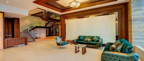 A spacious lobby with a staircase, a green sofa, and a patterned wall.
