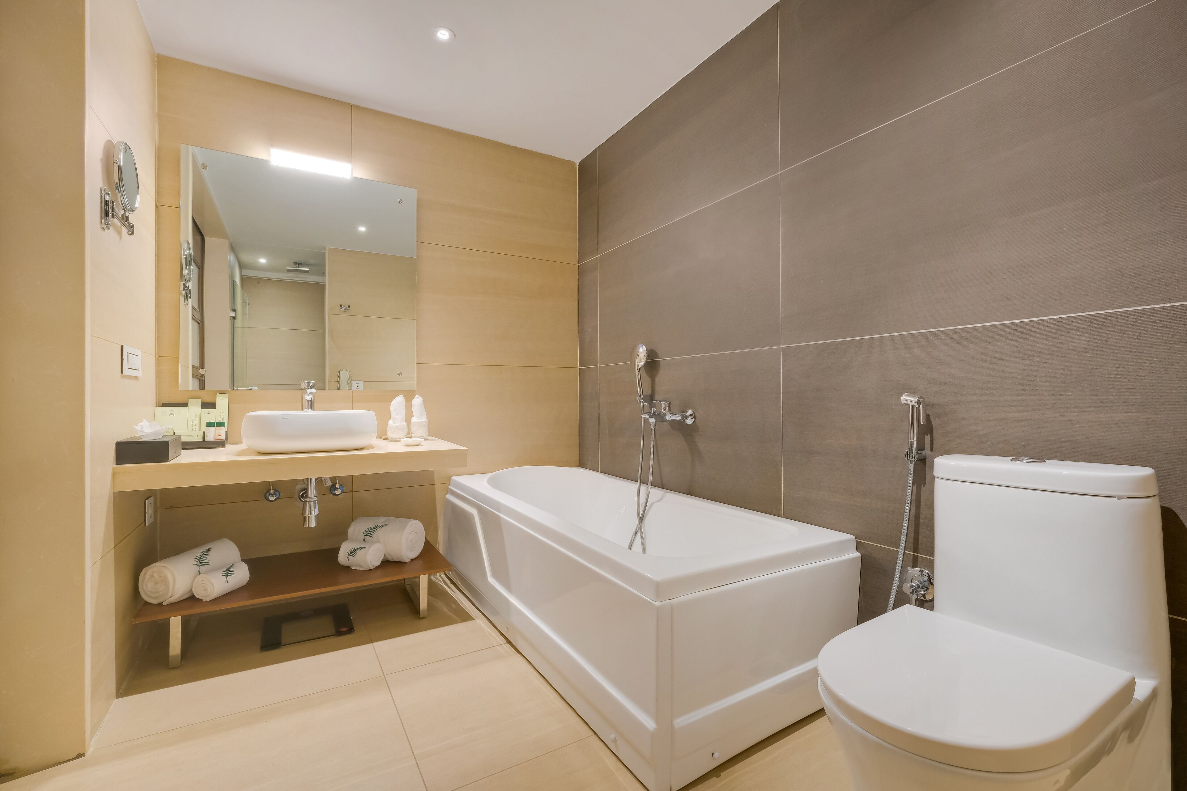 A modern bathroom with a bathtub, toilet, and vanity.