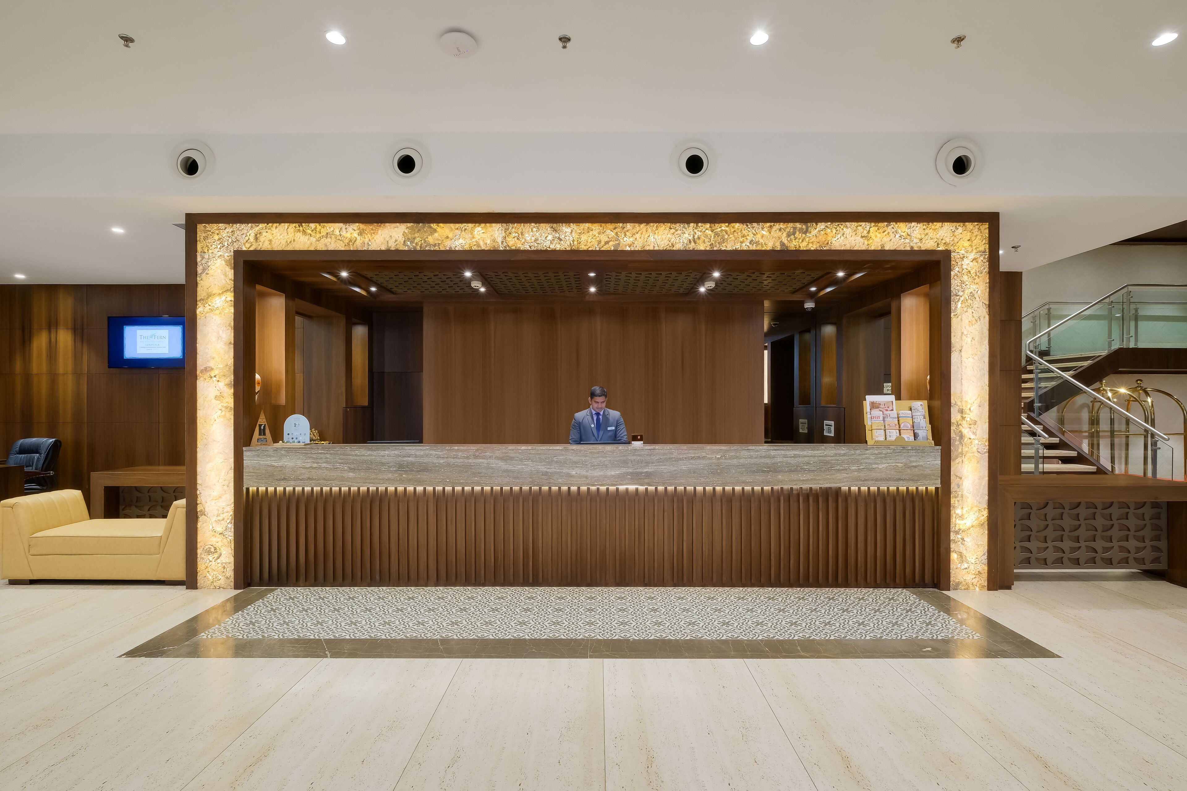 A reception area with a wooden reception desk, a sofa, and a television screen.