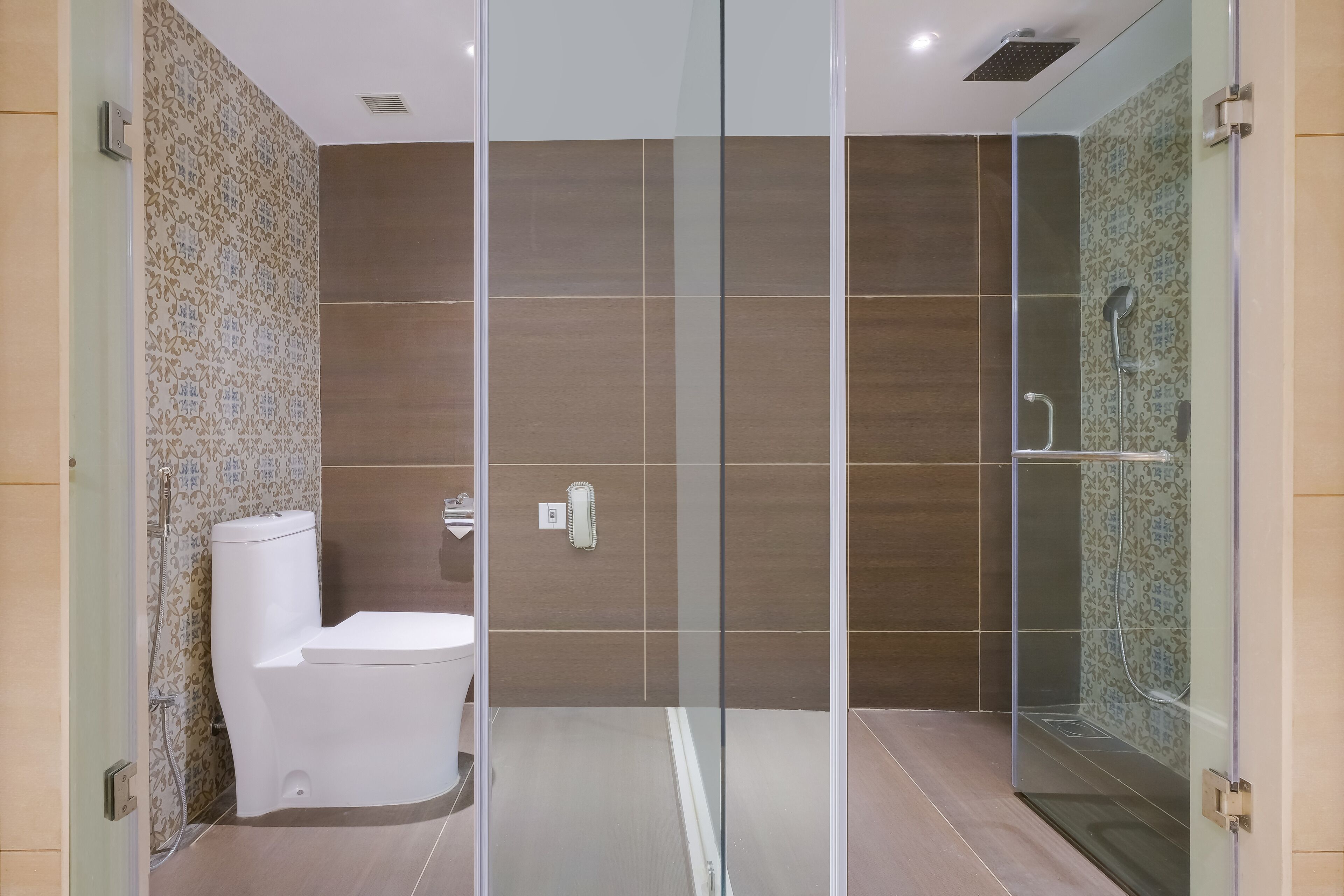 Un baño moderno con ducha de mampara de vidrio, inodoro y azulejos con diseño.