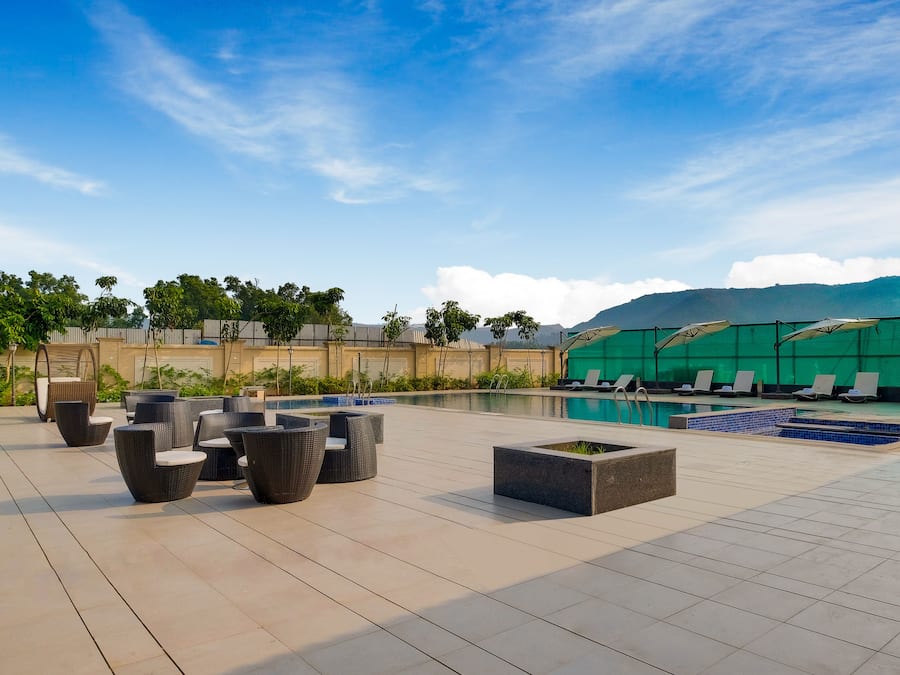 A rooftop pool area with lounge chairs and a view of a mountain.