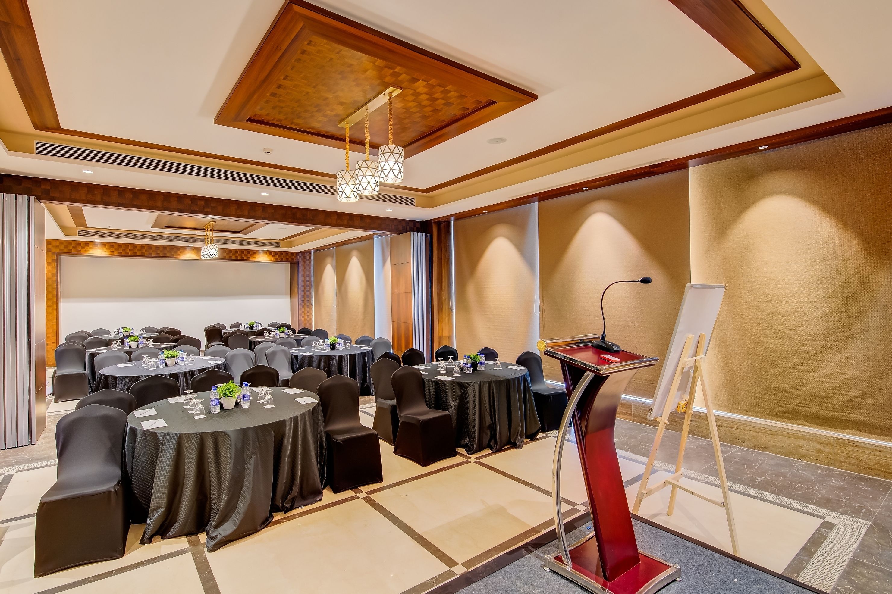 A conference room with round tables, black chairs, a podium, and a whiteboard.