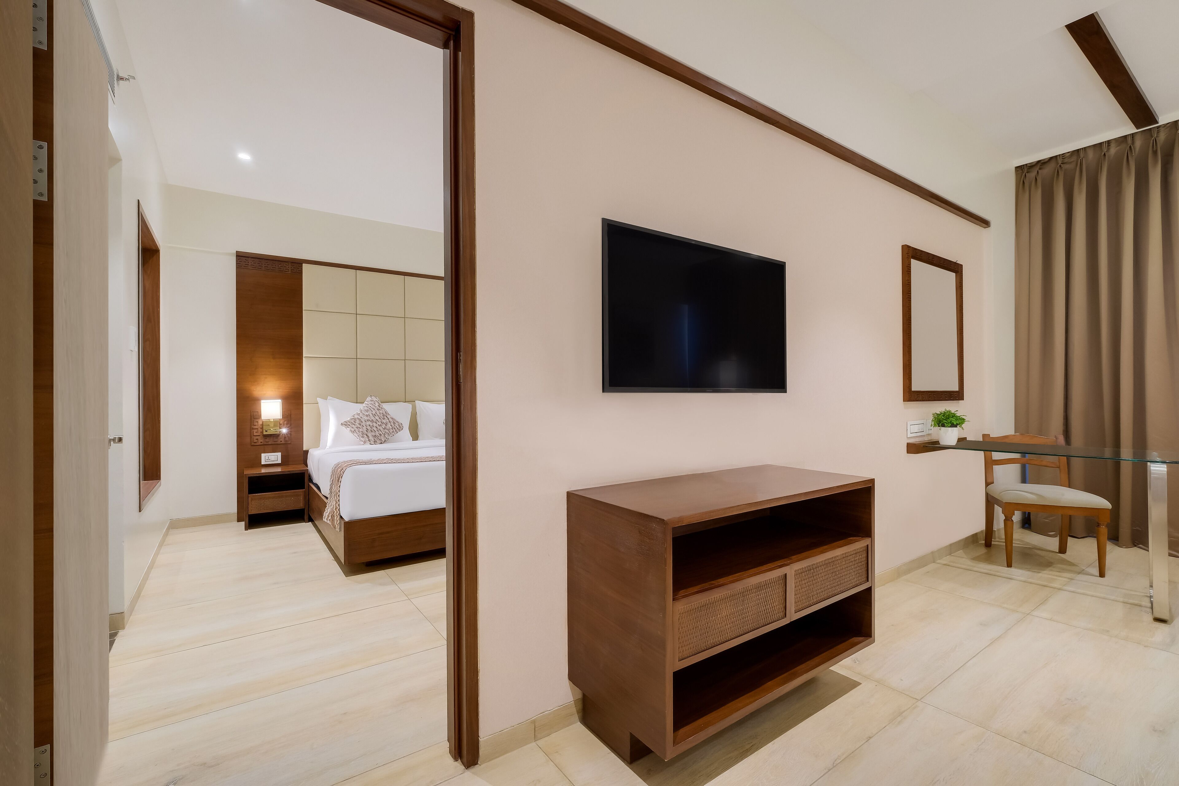 Une chambre d’hôtel moderne, équipée d’un lit, d’un téléviseur fixé au mur, d’une console en bois et d’une chaise.