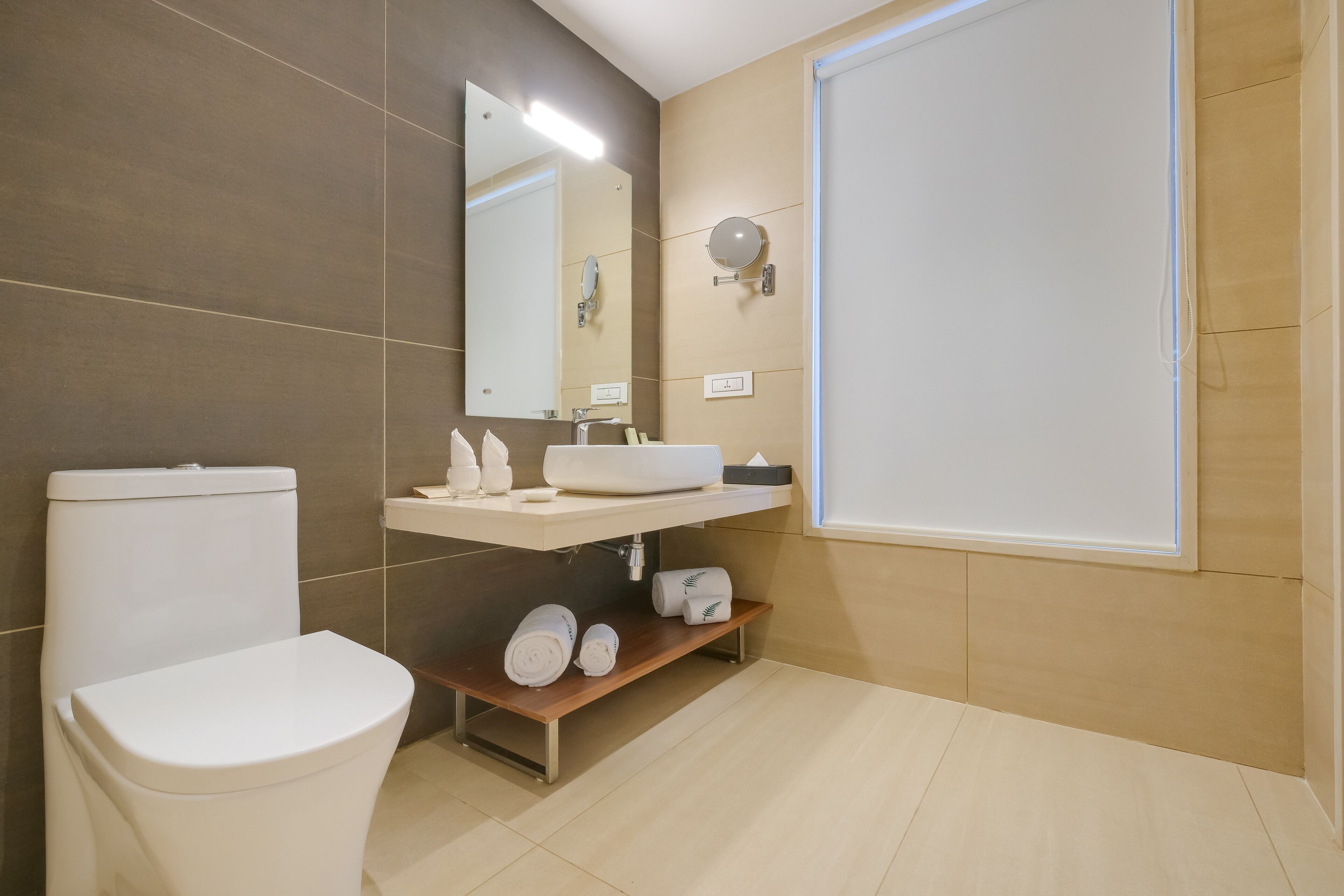 Un baño moderno con inodoro, lavamanos, espejo y ducha.