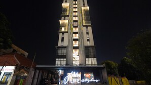 A modern hotel with a prominent vertical design, illuminated windows, and a neon sign advertising 'LIFE STYLE'. - Life Style Surabaya (Surabaya)