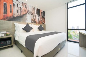 Una habitación de hotel moderna con una cama grande, una mesita de noche con un teléfono y un control remoto, un cuadro de un canal y un ventanal con vistas a la ciudad.