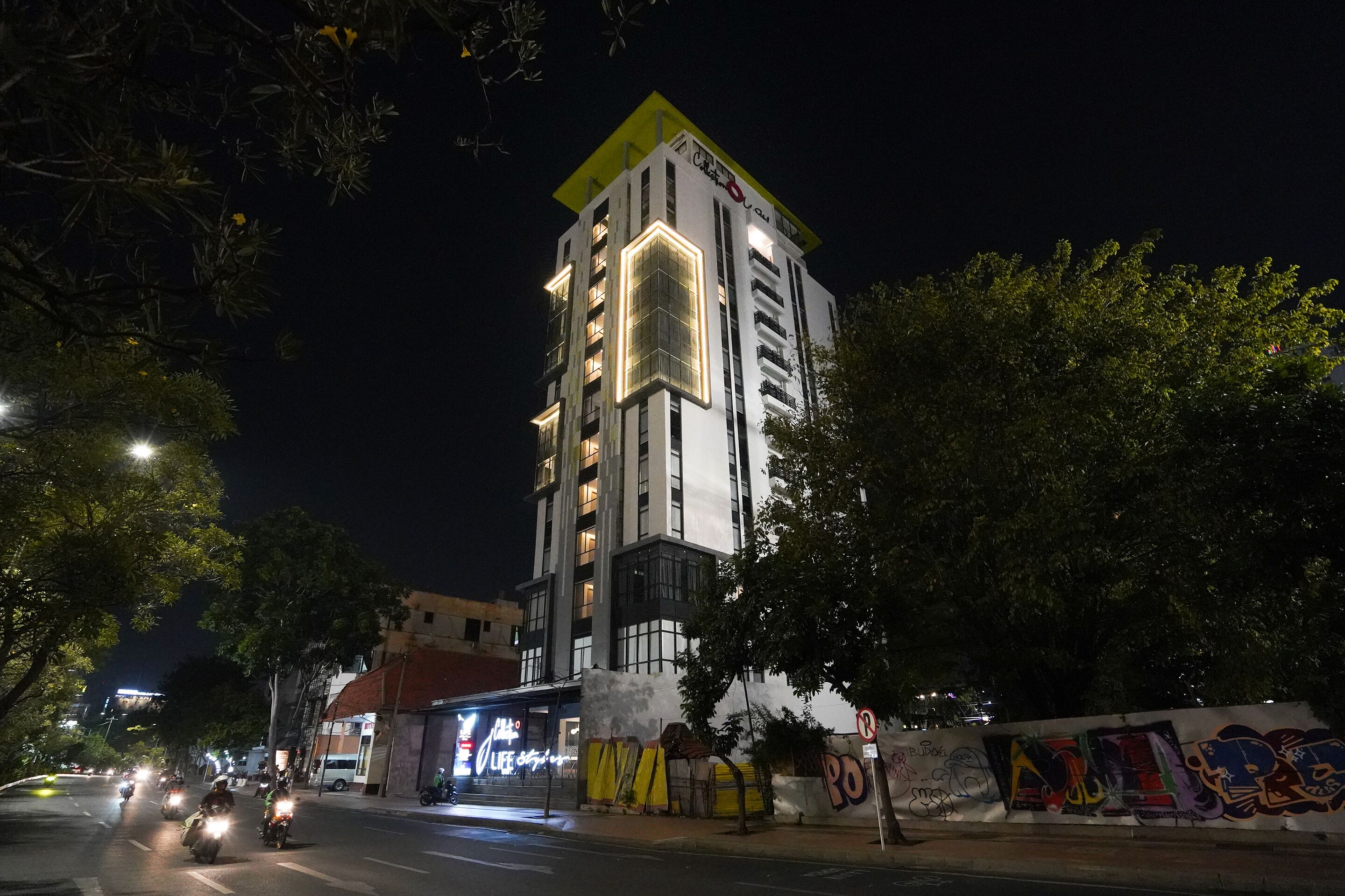 Un edificio de varios pisos con un característico techo amarillo y ventanas iluminadas al caer la noche.