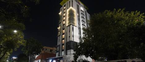 Un edificio de varios pisos con un característico techo amarillo y ventanas iluminadas al caer la noche.
