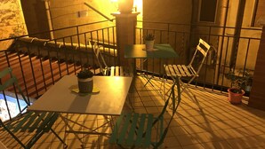 An outdoor patio with a table and chairs, a potted plant, and a railing. - B&b Il Cortile (Mazzarino)
