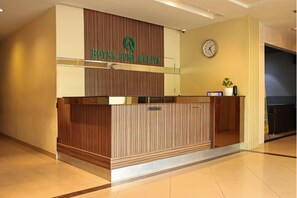 A reception desk with a clock and a potted plant. - Hotel O Bumi Malaya (Medan)