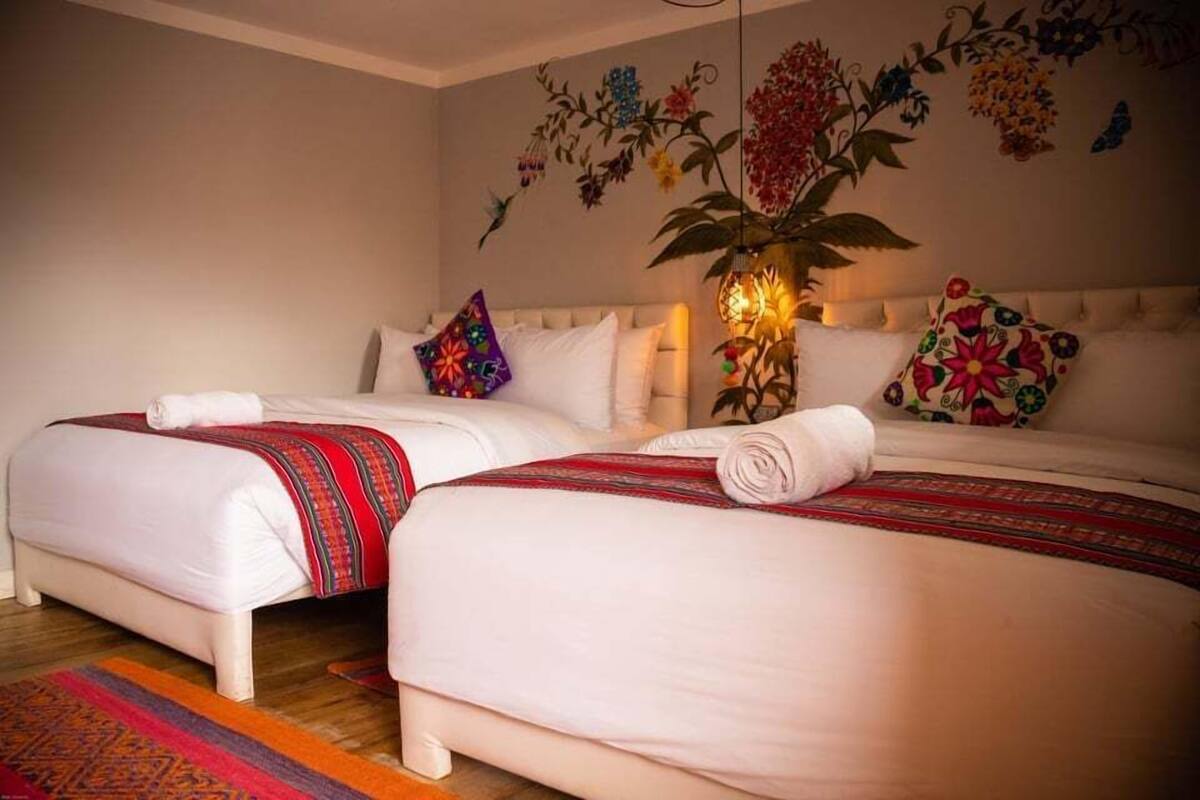 Un lit double avec une couvre-lit à motifs rouges et blancs, un oreiller blanc et un oreiller coloré.