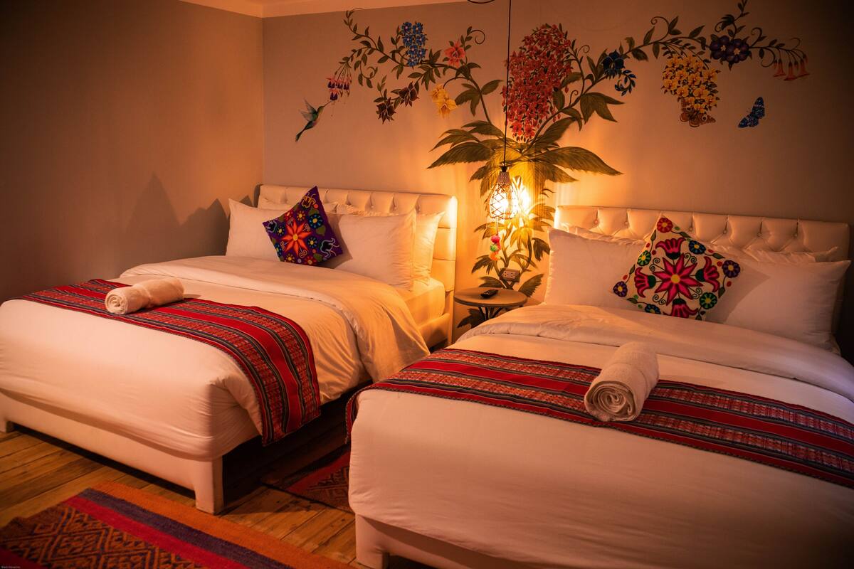 Une chambre d’hôtel avec deux lits, chacun recouvert d’une courtepointe à motifs rouges et blancs, et agrémentée d’oreillers blancs et d’une décoration murale.