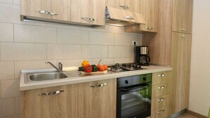 Una cuina moderna amb armaris de fusta, un rentapeus d'acer inoxidable, una cuina a gas i un forn encastat.