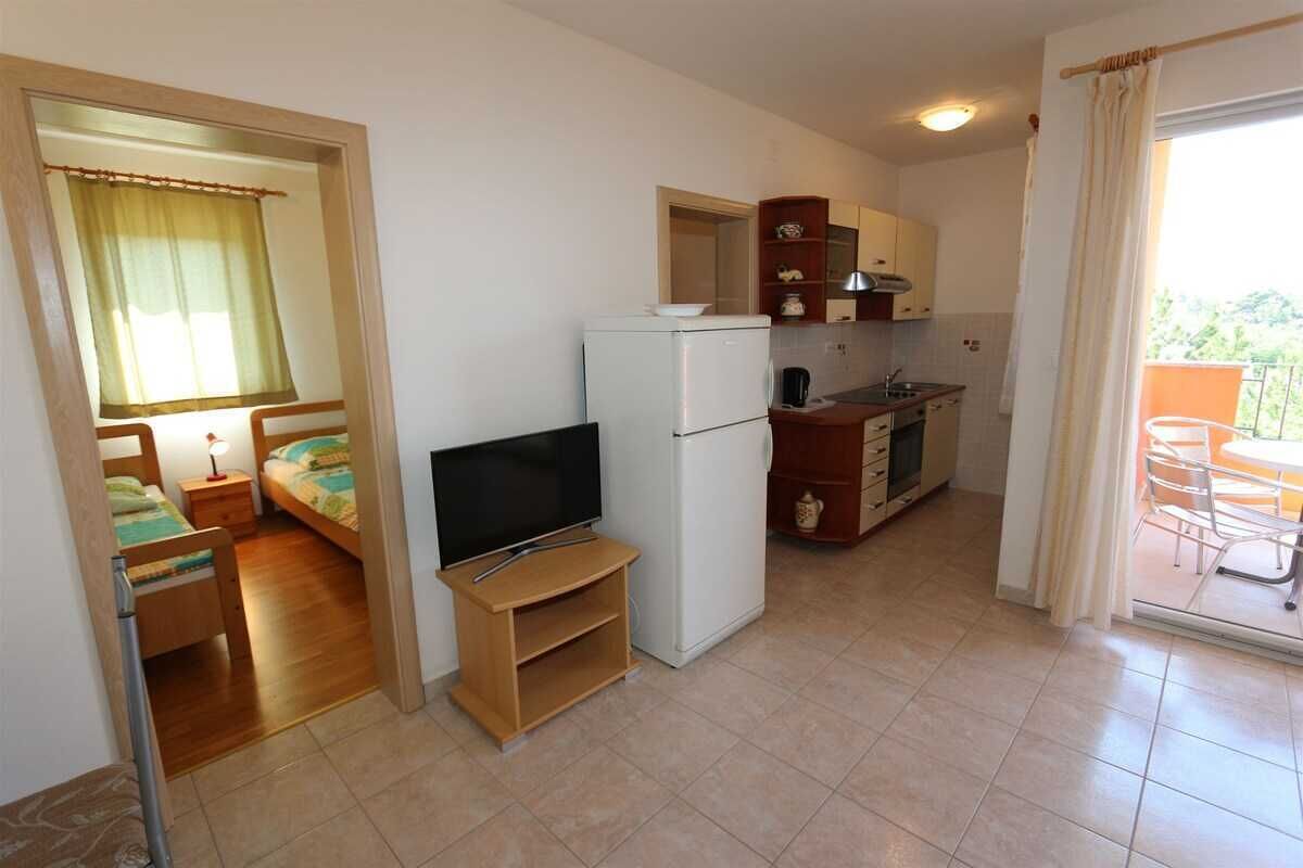 Ein kompakter Wohnraum mit Küchenzeile, Fernseher, Essbereich und Balkon.