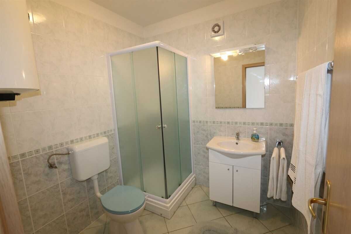 A bathroom with a toilet, a glass-enclosed shower, a sink, and a mirror.