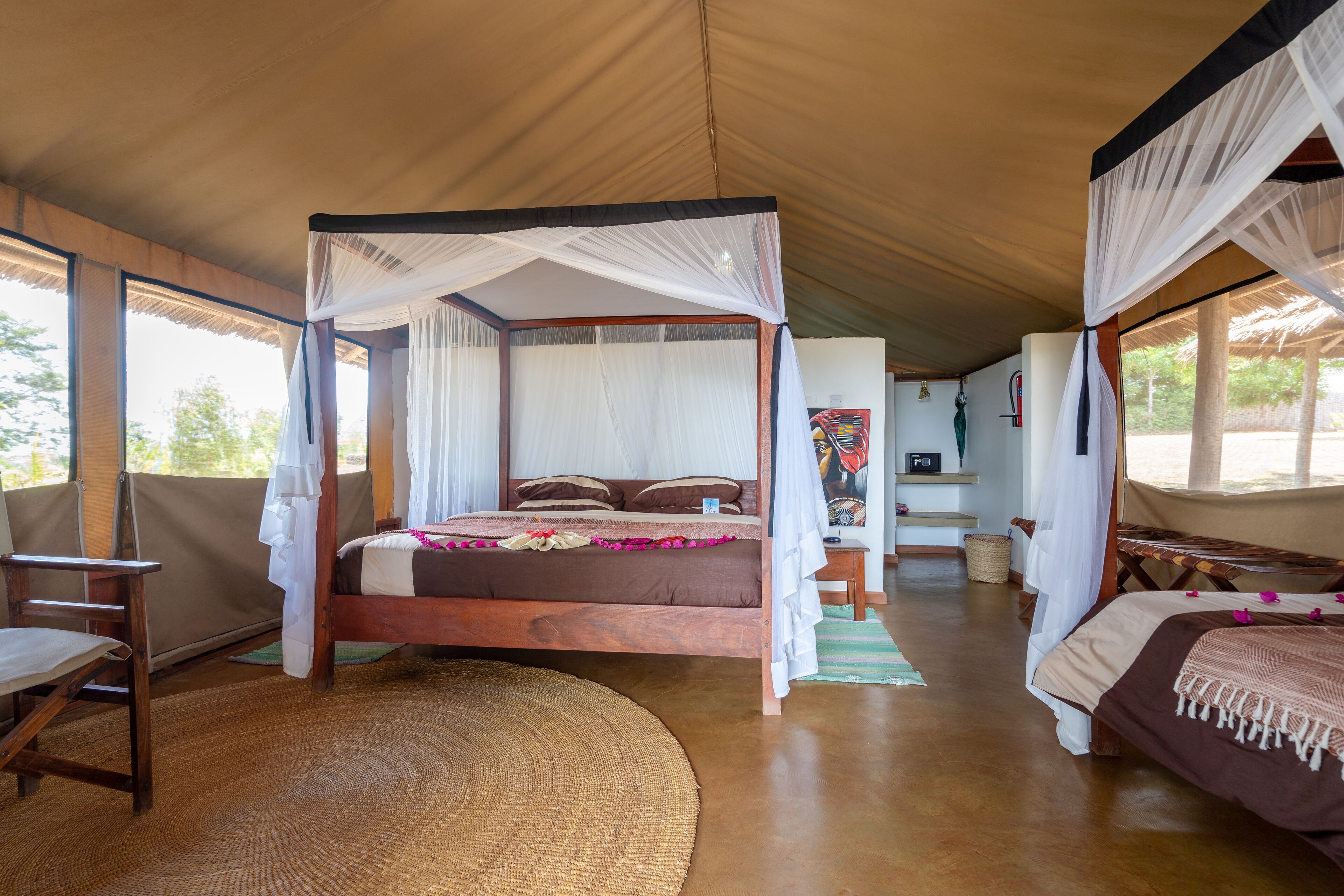 A spacious room with a large bed, a wooden chair, and a small table.