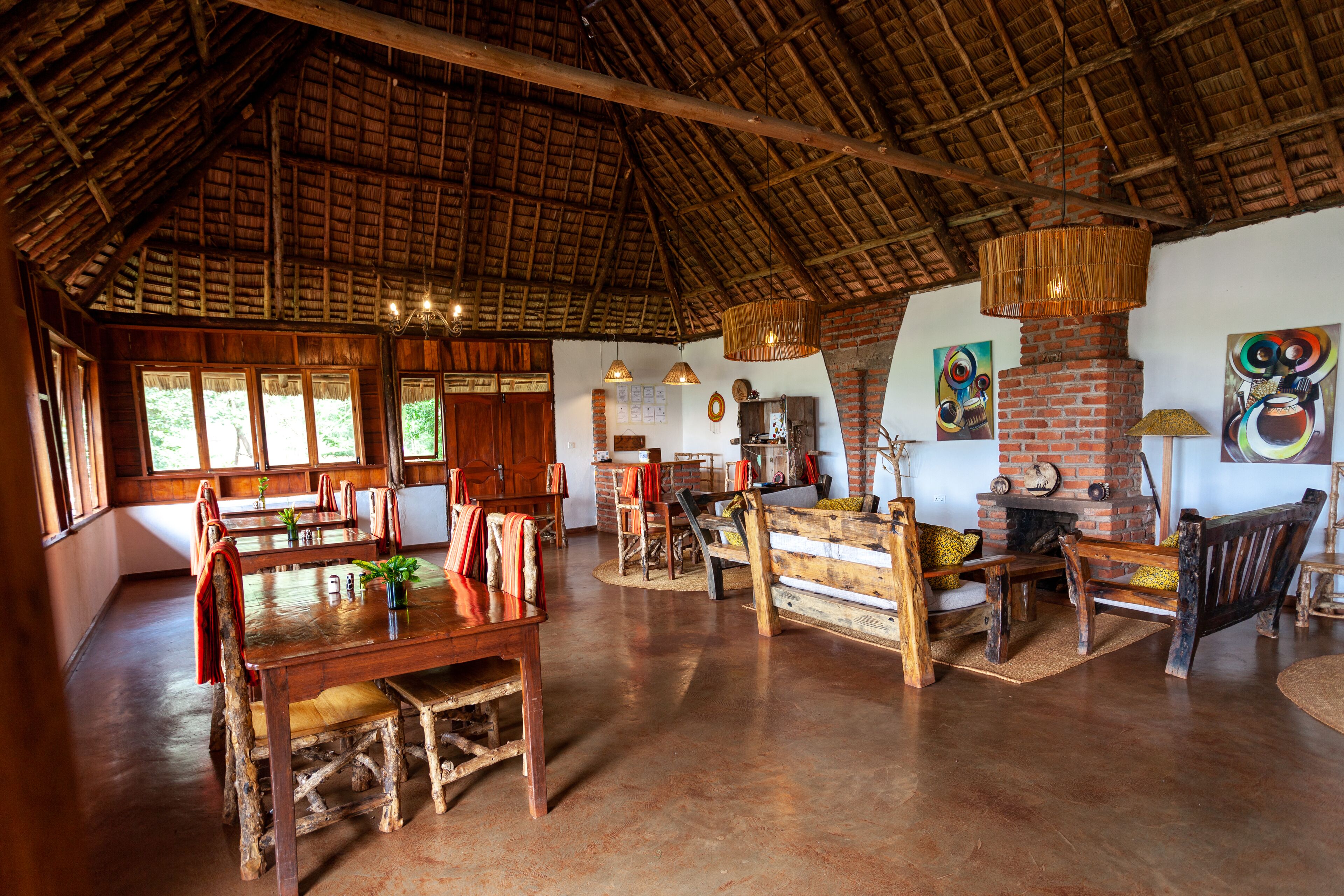Un interior rústico con techo de madera alto, chimenea de ladrillo y mobiliario de madera.