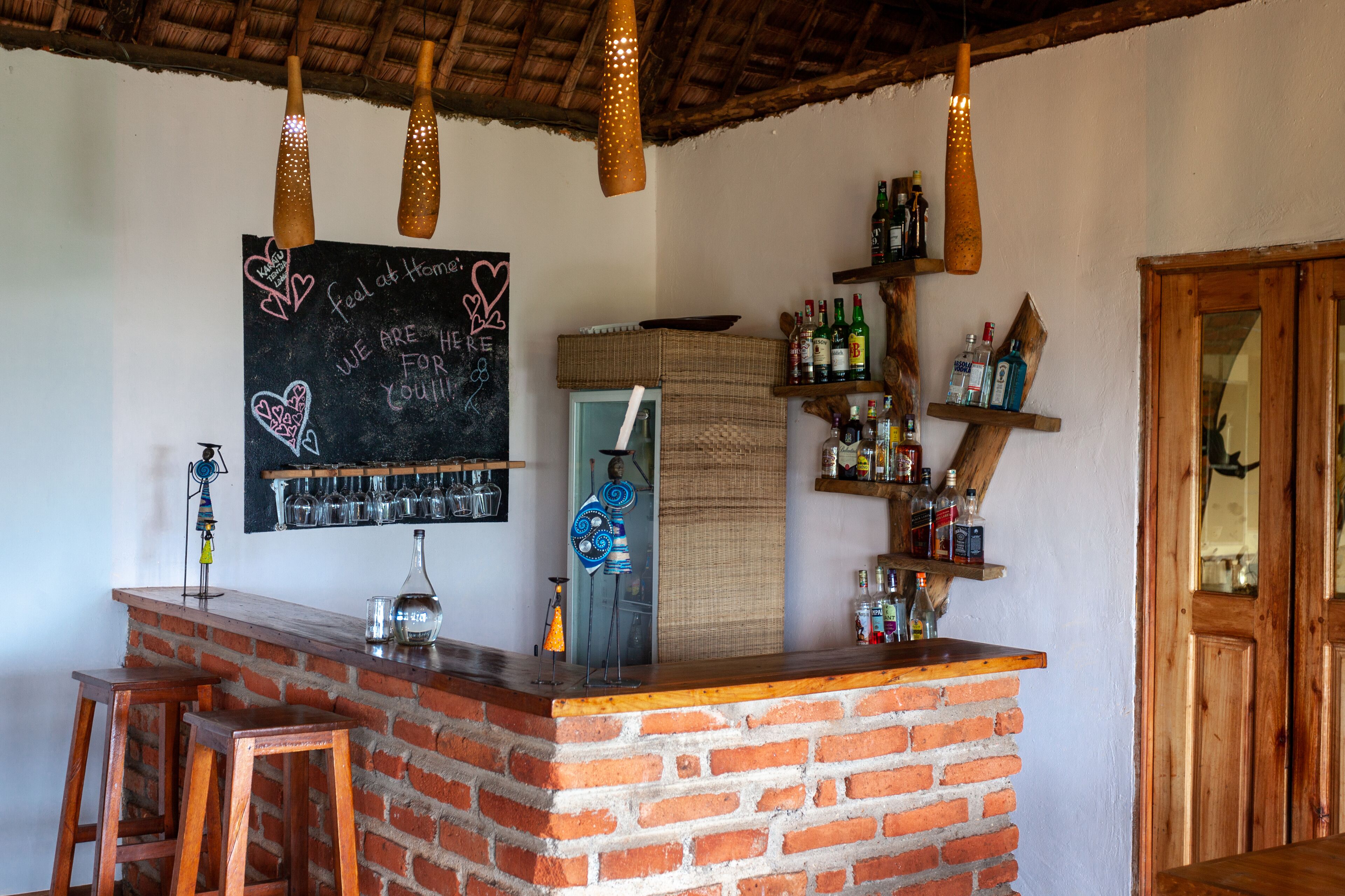 A bar area with a brick counter, hanging lights, and a chalkboard with a message.