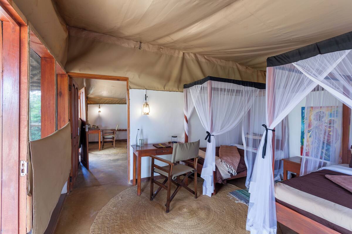 A room with a bed, a desk, and a chair. There is a canopy over the bed.