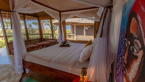 Um quarto com uma cama, um quadro e vista para o exterior.