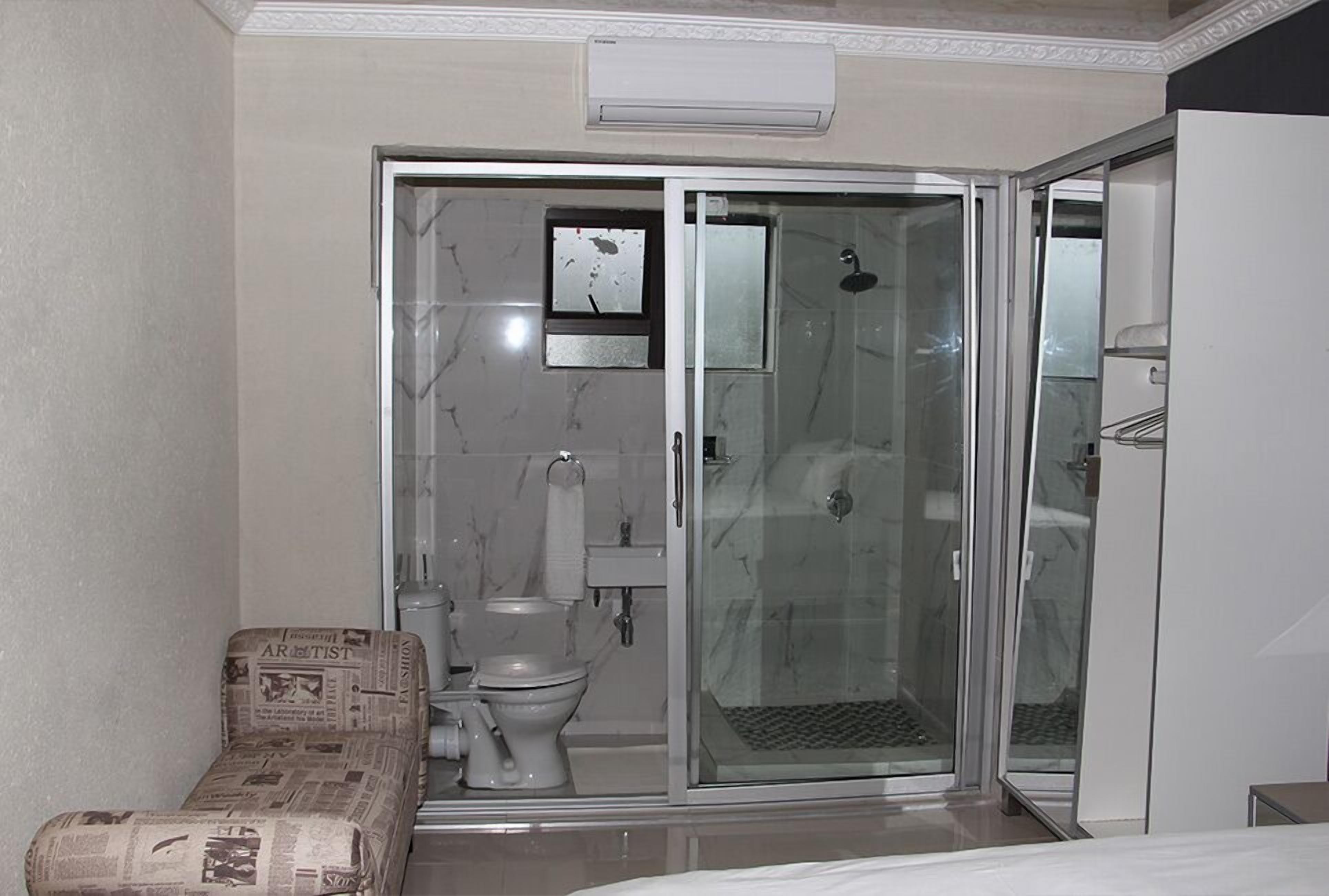 Une salle de bain avec une douche à parois de verre, des toilettes et un lavabo.