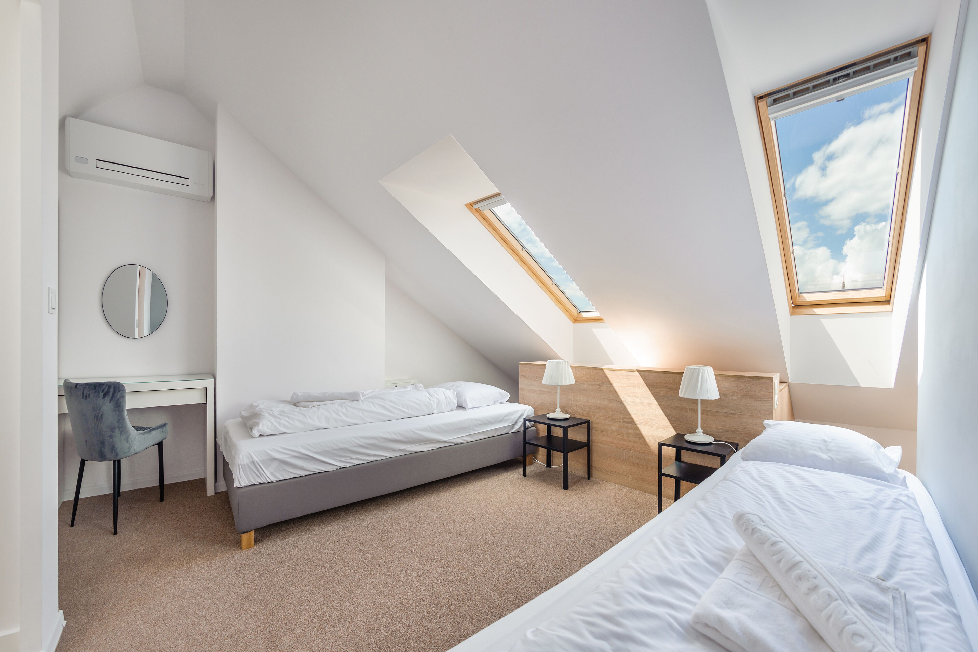 A modern bedroom with a skylight, a desk, and two beds.