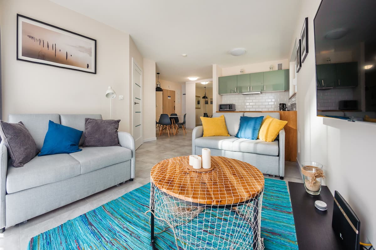 A modern living room with a grey sofa, a round coffee table, and a colorful rug.