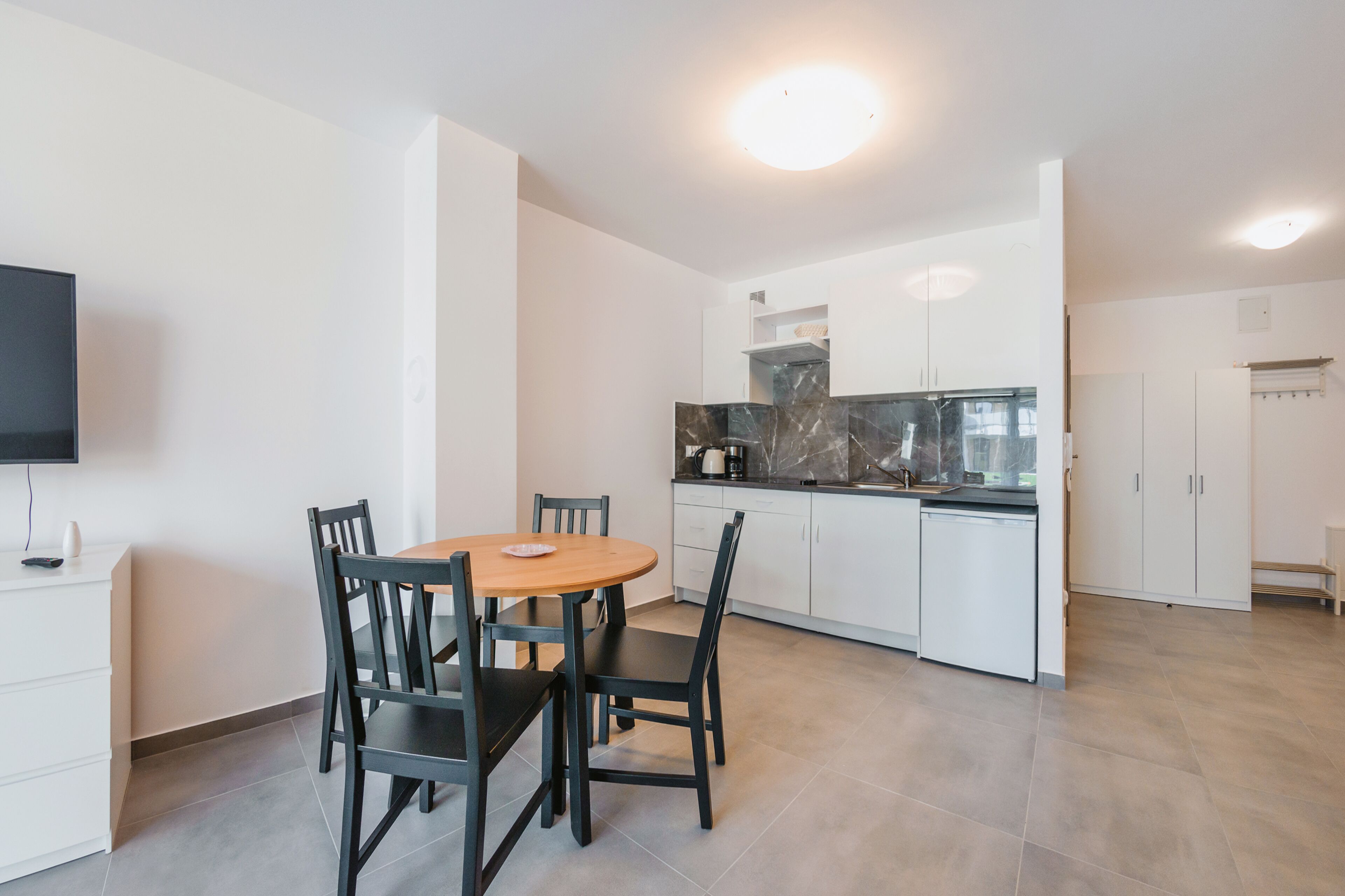 A modern kitchen with white cabinets, a marble backsplash, and a built-in oven.