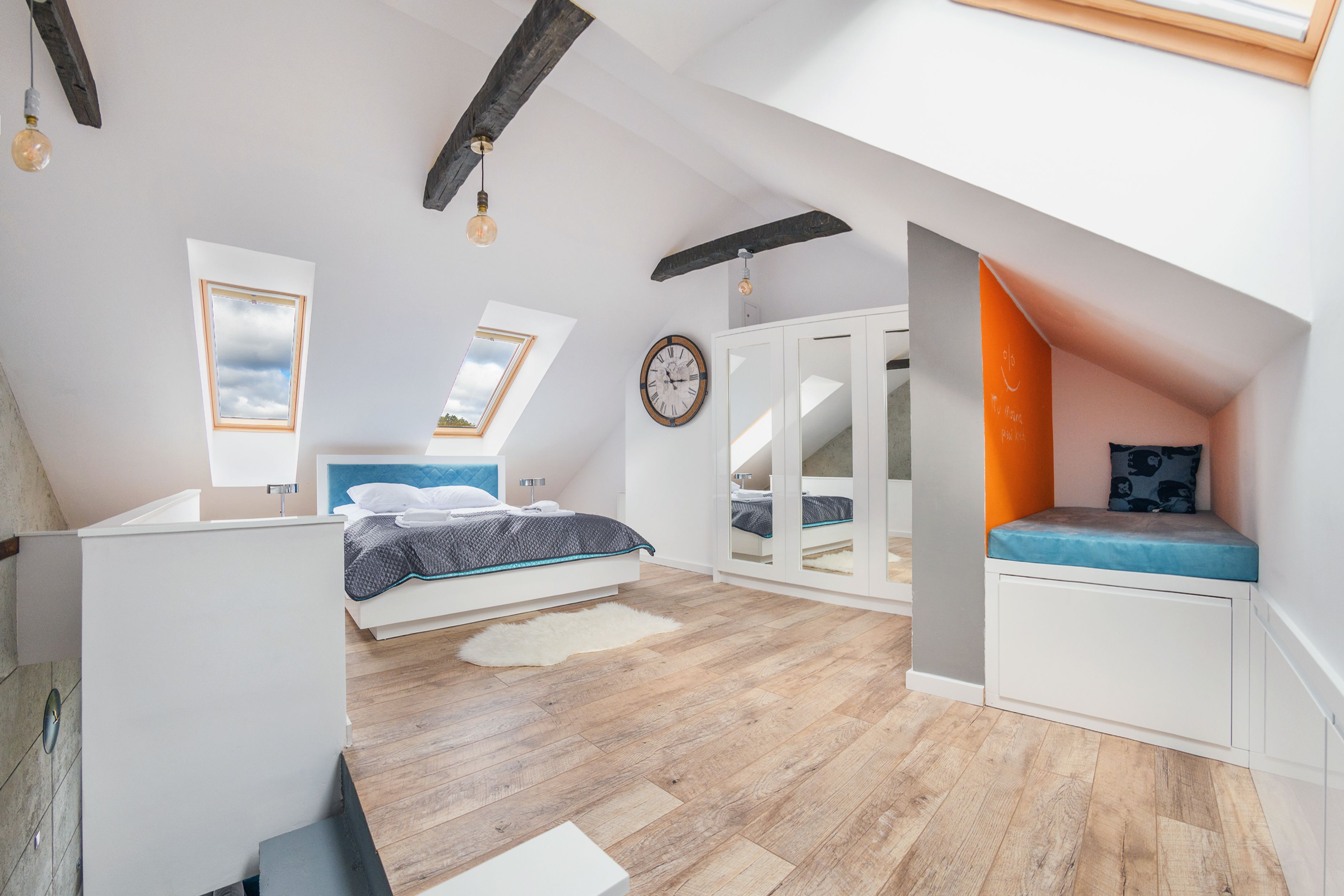 Une chambre moderne avec une lucarne, un lit, une armoire et un banc intégré.