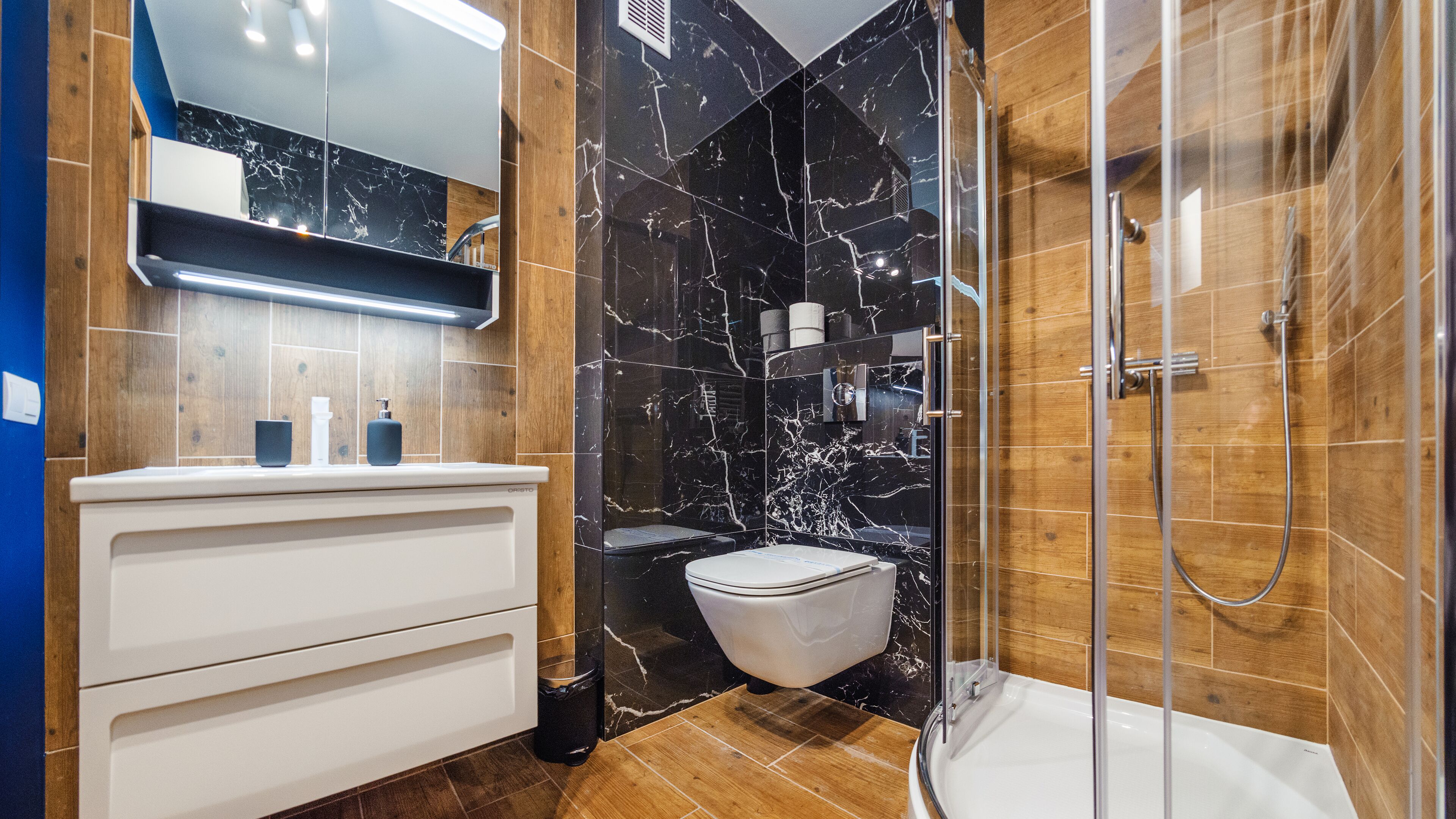 A modern bathroom with a marble vanity, a toilet, and a glass-enclosed shower.