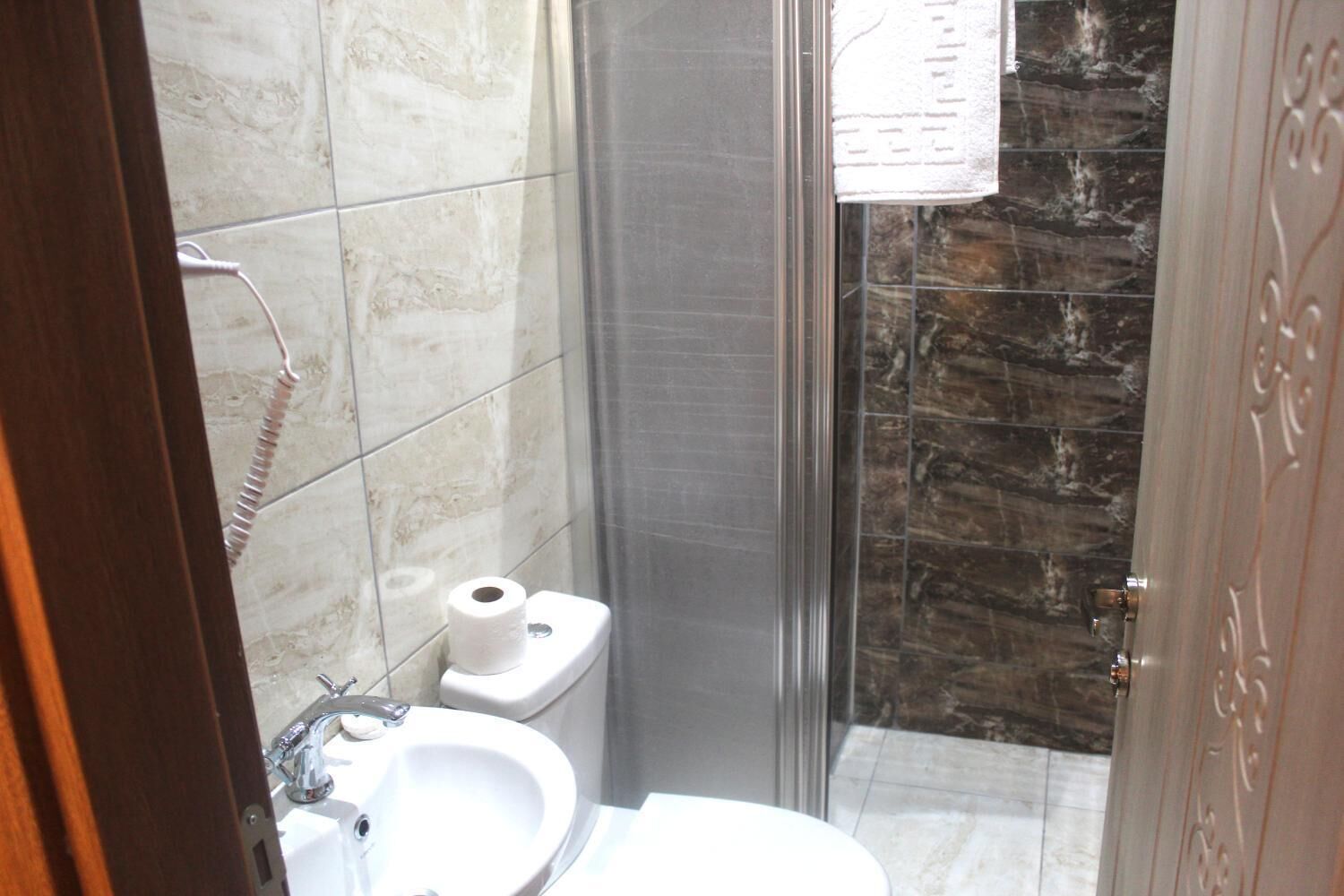 A bathroom with a toilet, sink, and shower.