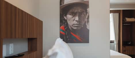 A hotel room with a bed, a wooden wardrobe, and a wall-mounted artwork.