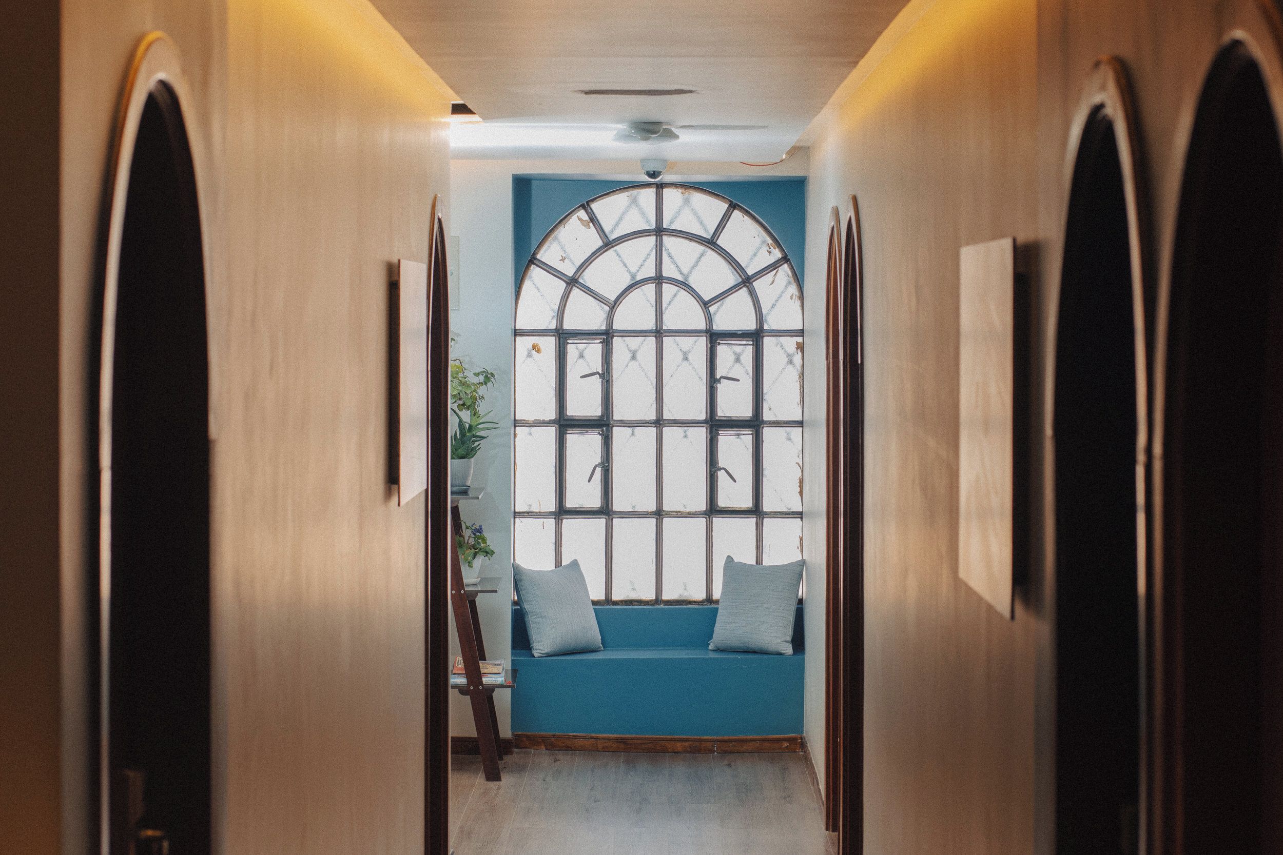 A narrow hallway with a bench and a large window with a grid pattern.