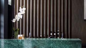 A reception desk with a green marble top, a hanging spherical light fixture, and a vertical wooden slat wall. - DREAM By Stannum Hotel (La Paz)