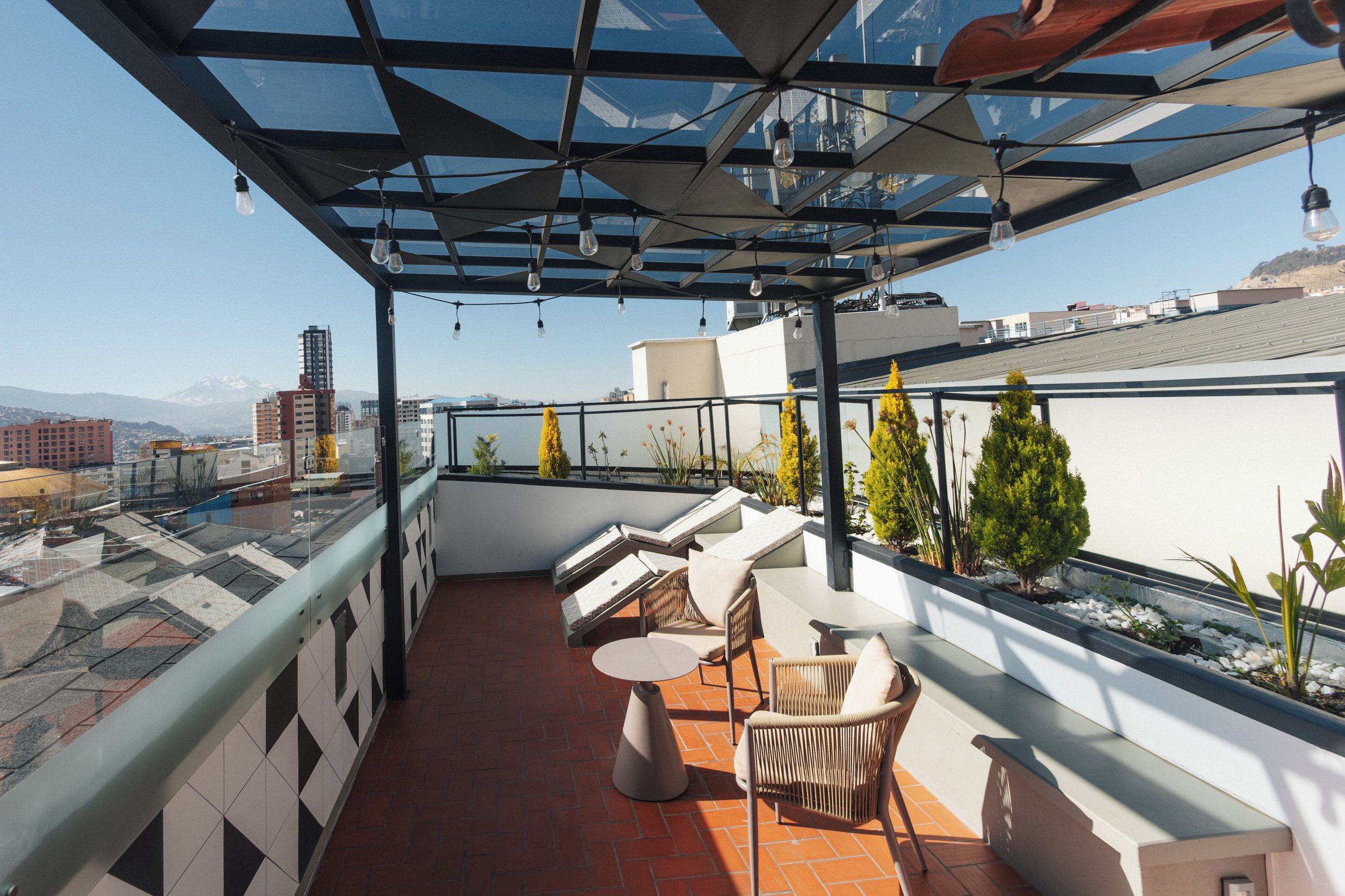A rooftop terrace with outdoor seating, a glass ceiling, and a city view.