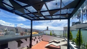 A rooftop terrace with a glass ceiling, outdoor seating, and a view of the cityscape. - DREAM By Stannum Hotel (La Paz)