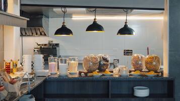 Una barra de desayuno con opciones de cereales y dispensadores de leche.