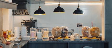 Una barra de desayuno con opciones de cereales y dispensadores de leche.