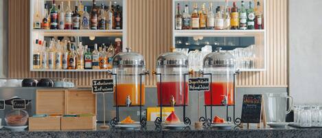 Zona de bar con estantes llenos de botellas de licores, dos dispensadores de bebidas y un menú en pizarra.