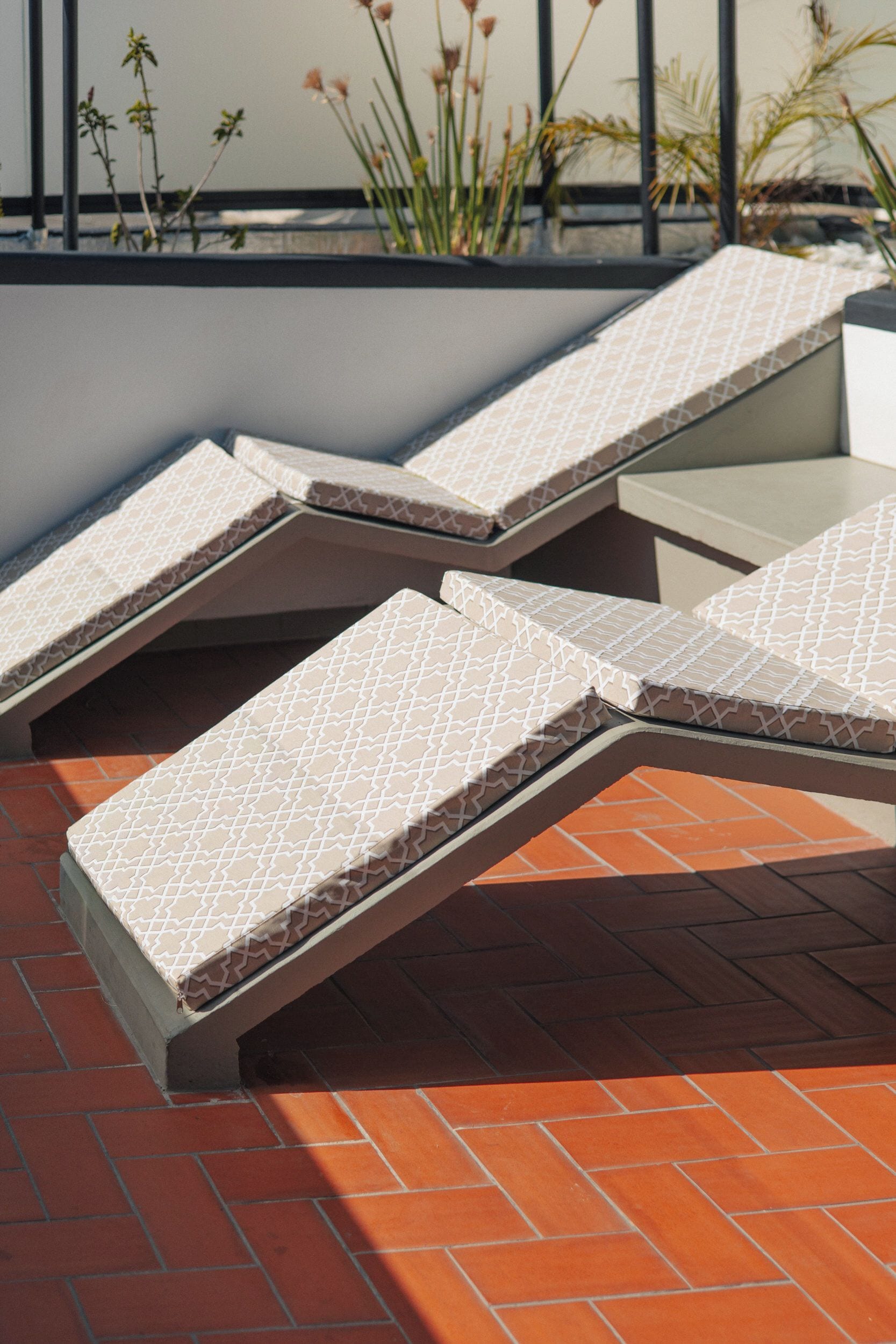 A rooftop terrace with sun loungers and a small table.