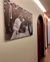 Un pasillo con una fotografía enmarcada en la pared, una puerta de madera y un cartel con un número.