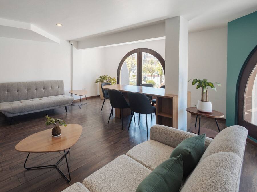Una sala moderna con un sofá, una mesa de centro y un comedor con sillas y una mesa.