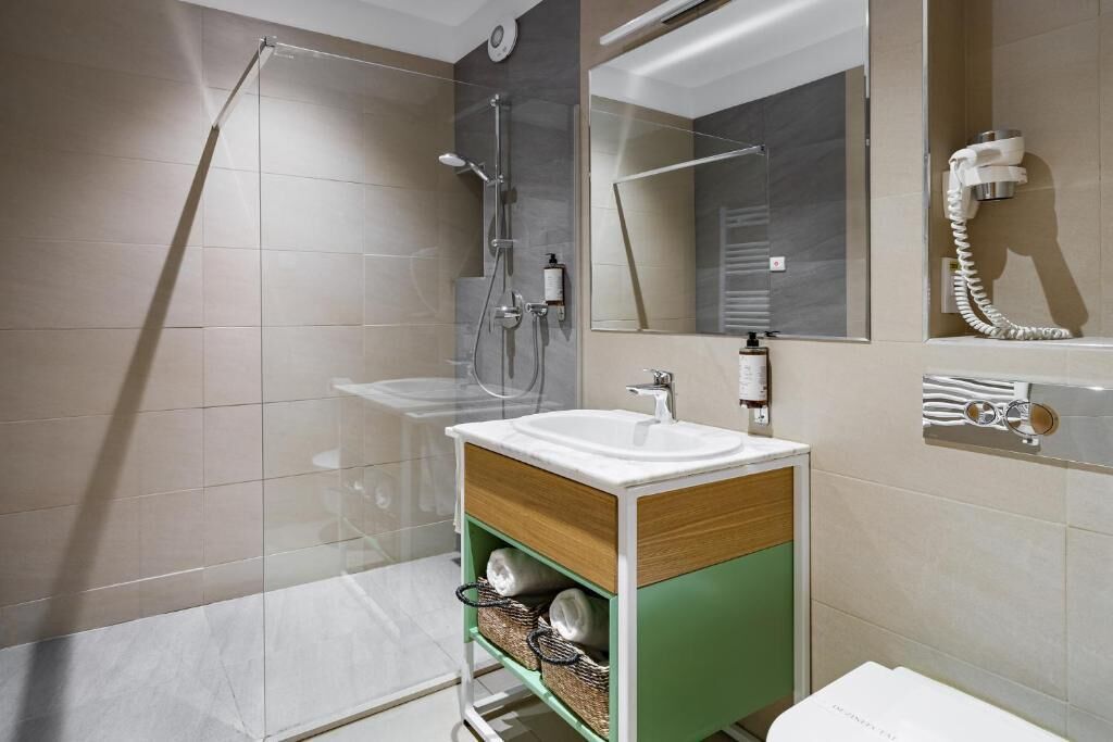 A modern bathroom with a glass shower enclosure, a white sink, and a green vanity.