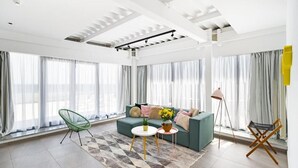 A modern living room with a green sofa, a green chair, a small white table, and a floor lamp.