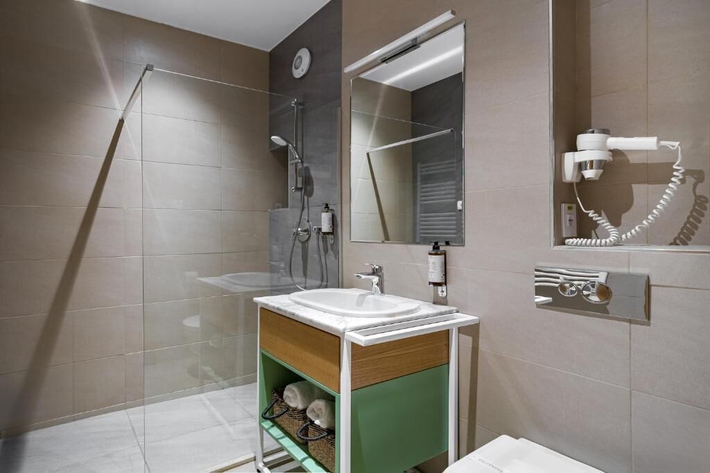 Un baño moderno con cabina de ducha de vidrio, un lavabo con espejo y un perchero para toallas.